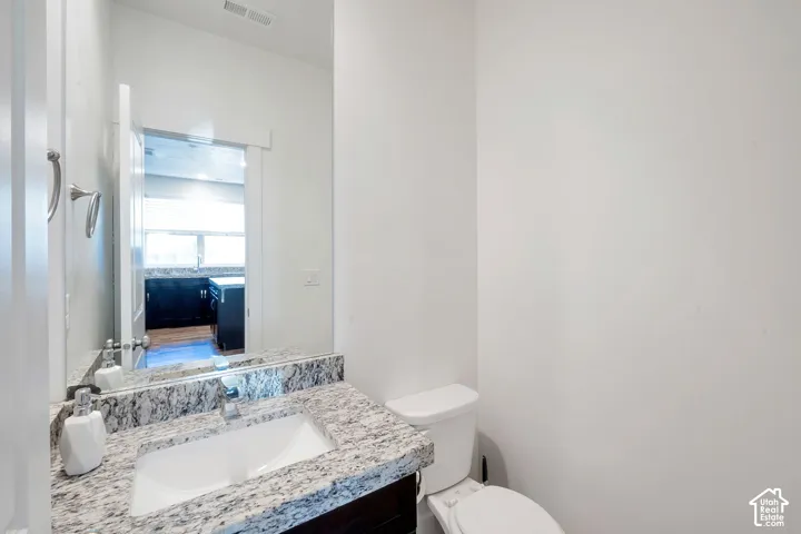 Vanity with stone countertop, undermount sink, and chrome faucet