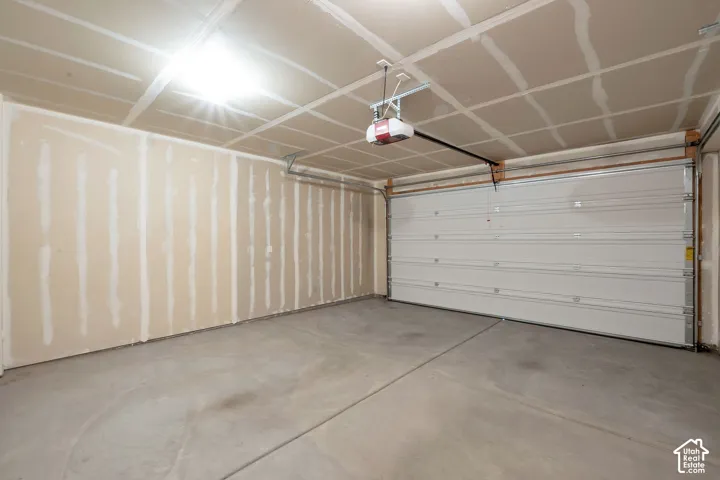 Spacious garage with a concrete floor, overhead lighting, and an automatic garage door opener