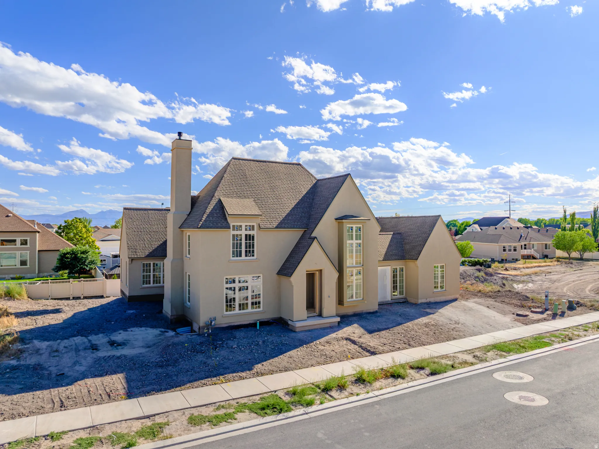 Stucco exterior with a prominent chimney, multiple gables, and varied window styles