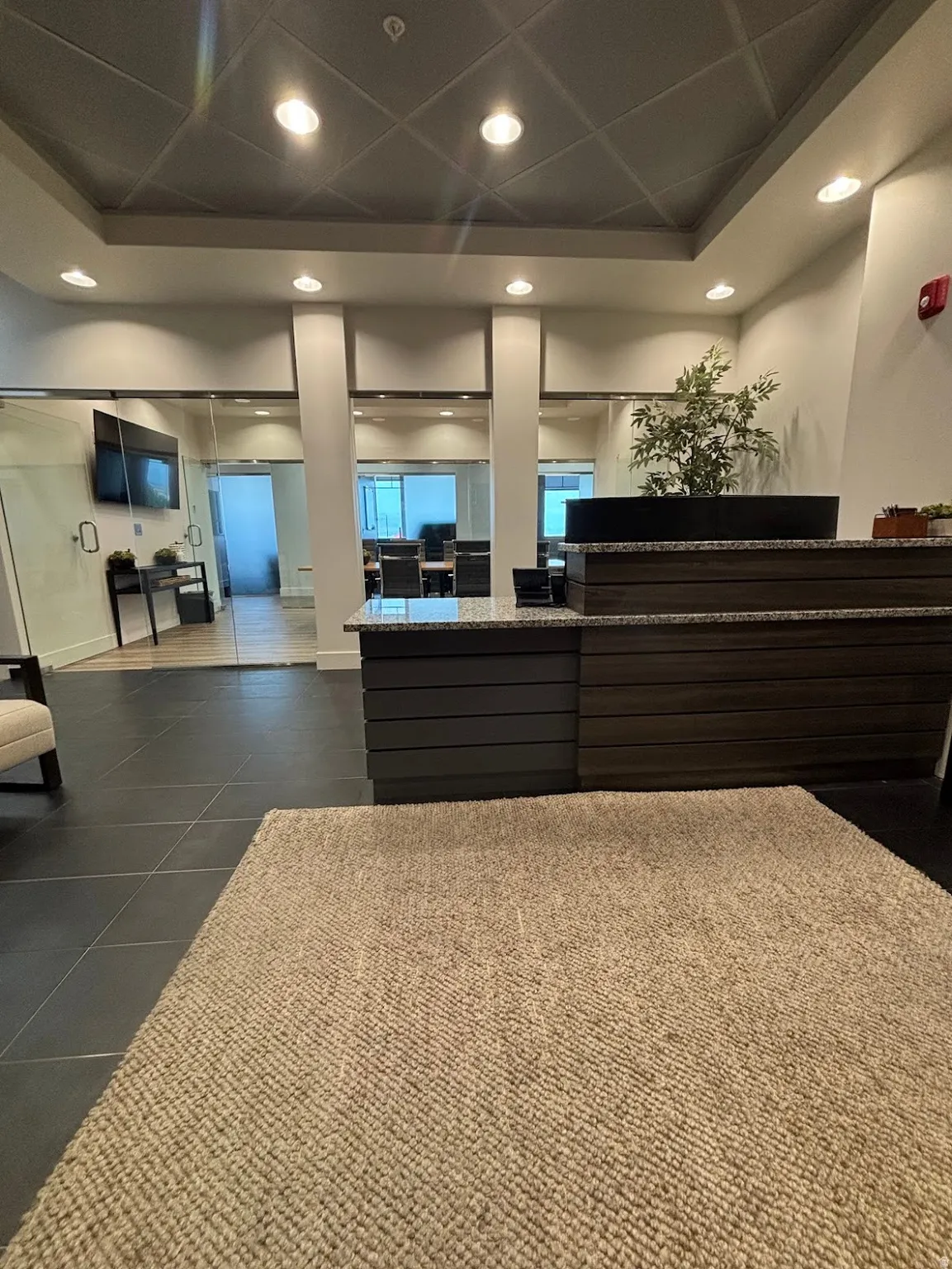 Lobby area featuring a reception desk with a stone countertop, dark wood-finish paneling, and recessed lighting