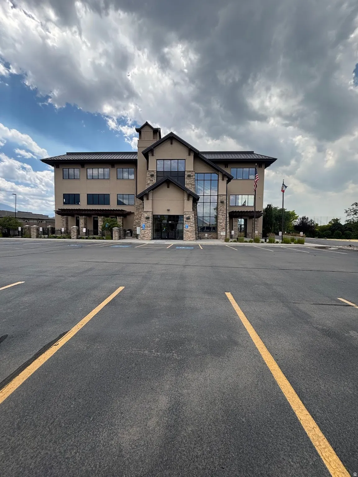 Contemporary commercial building featuring a stone and stucco facade with lots of parking spots.