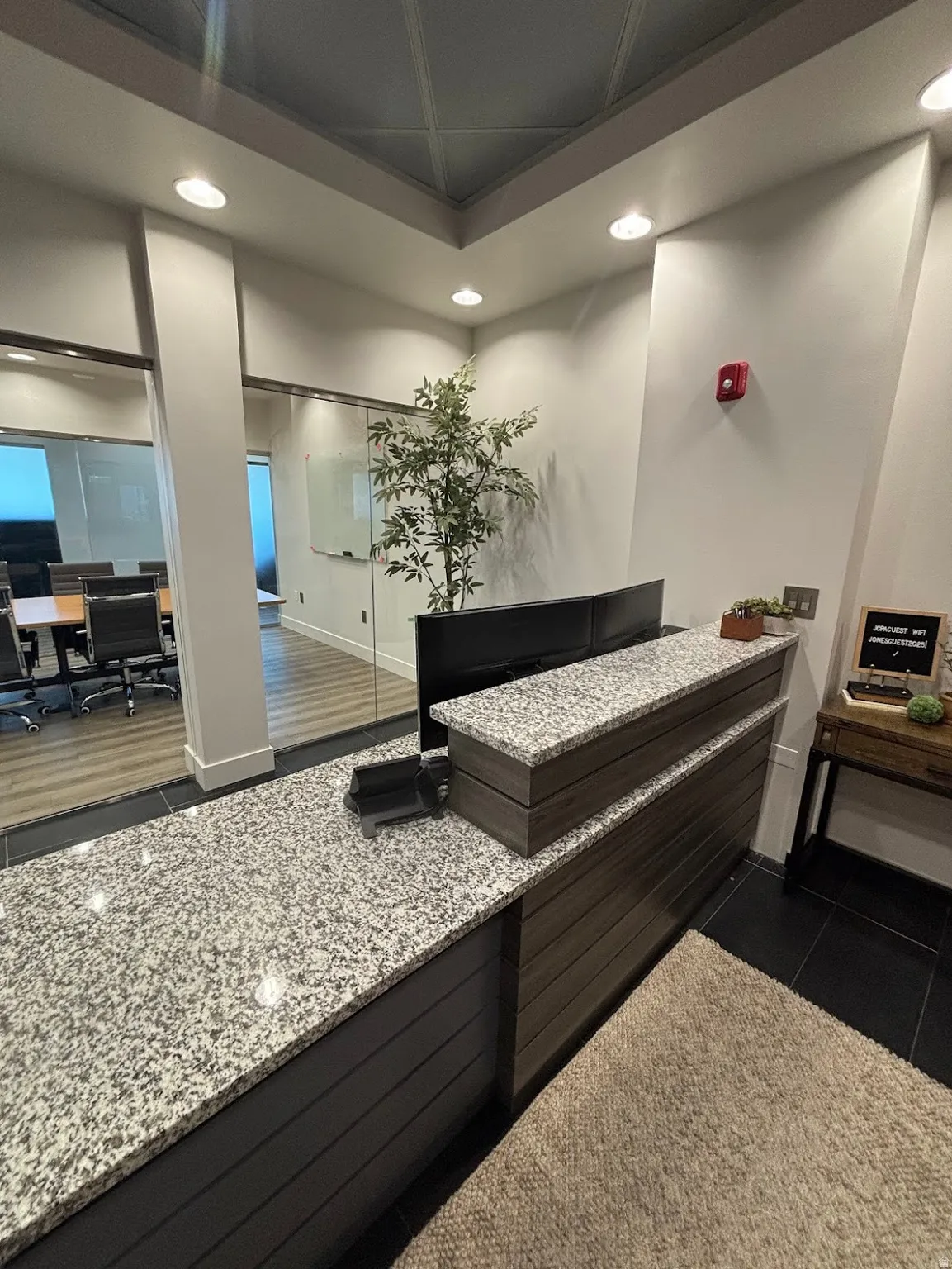 Reception area featuring a multi-level granite-topped desk with wood-finish paneling