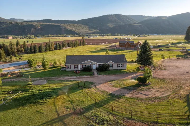 Ranch-style residence featuring a prominent front entrance, attached garage, and mature landscaping