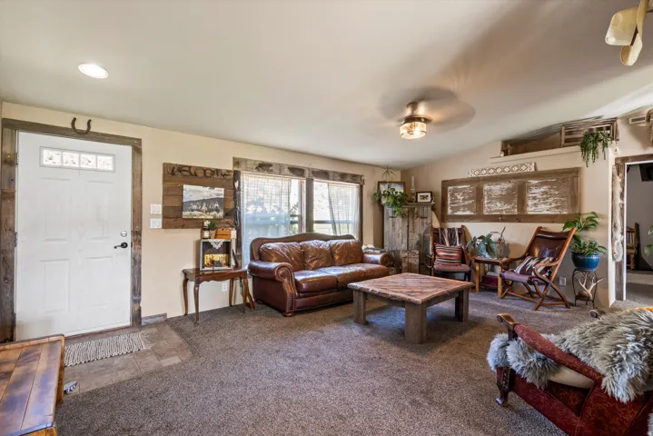 Living area featuring a textured carpet floor, a white paneled entry door with transom-style windows, and recessed ceiling lighting