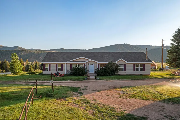 Ranch-style residence featuring a light-colored exterior with contrasting deep red shutters