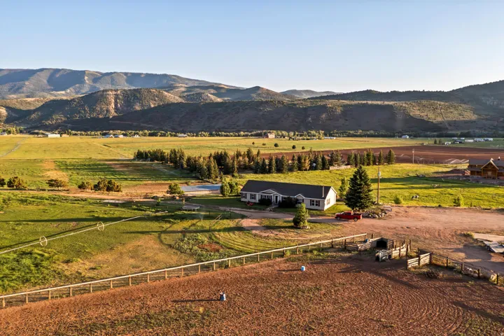 Expansive property featuring a ranch-style residence, a riding arena, and surrounding open fields