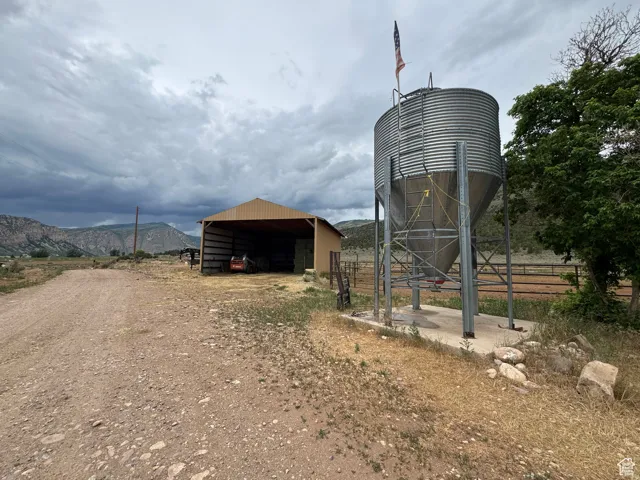 Galvanized steel grain silo on a concrete pad, accompanied by a spacious open-sided barn