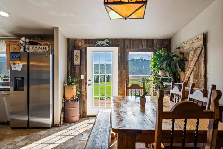 Dining area featuring a wood-finish table, matching chairs, and a white paneled door with glass inserts opening to a grassy expanse