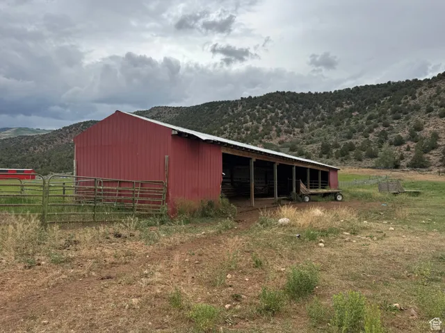 Red barn structure with a metal roof and open-sided stalls