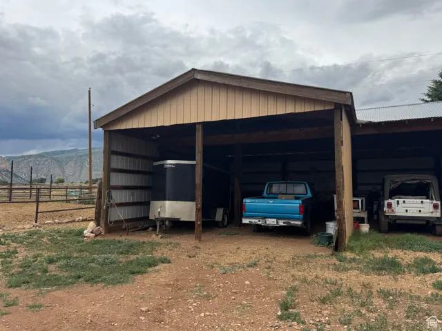 Open-sided barn structure featuring a corrugated metal roof and wood posts
