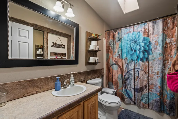 Bathroom featuring a white oval sink, an expansive countertop, a framed mirror, and a wall-mounted light fixture