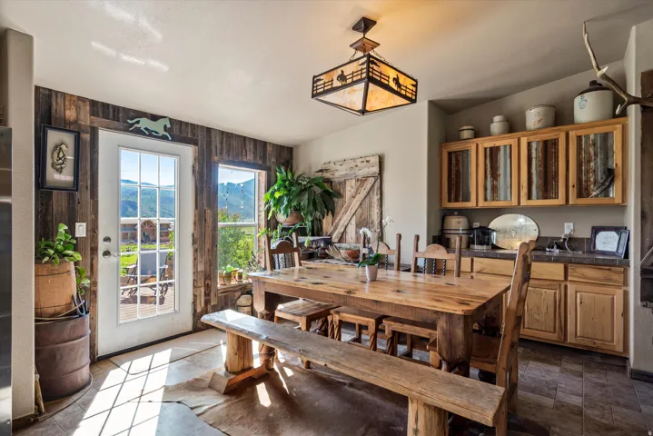 Dining area featuring a rustic wood-plank accent wall, a glass-paned door, and an expansive window