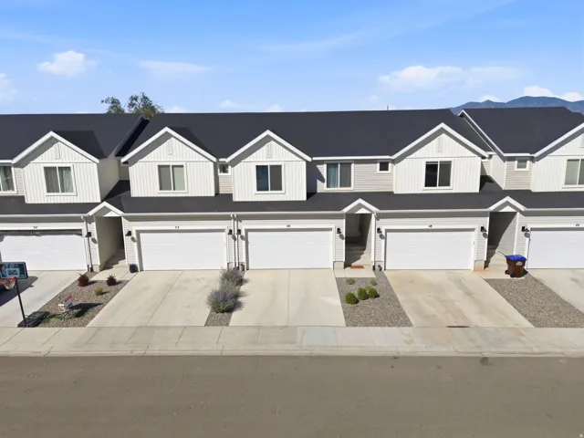 Contemporary townhome row featuring light-colored siding with dark shingled roofs