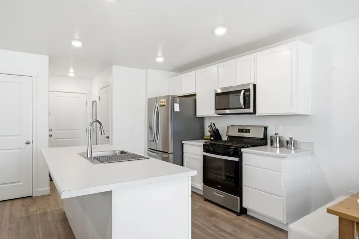 Contemporary kitchen featuring white cabinetry, light-toned countertops, and wood-finish flooring