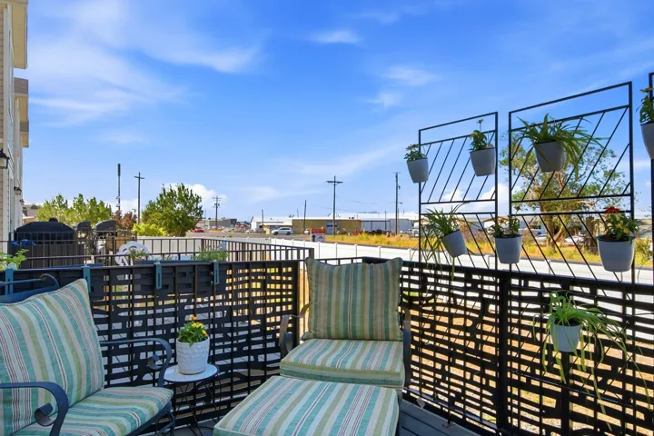 Exterior balcony featuring a lattice privacy screen, metal railings, and decorative hanging planters