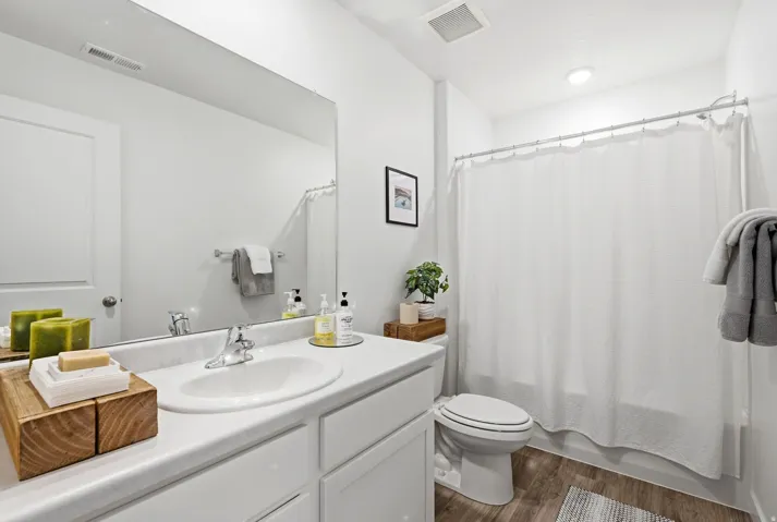 Contemporary bathroom featuring a white vanity with integrated sink, chrome faucet, and expansive wall-mounted mirror
