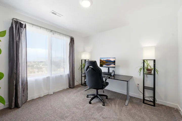 Open-concept room featuring a large window with sheer and blackout drapes, recessed ceiling lighting, and light-colored carpeting