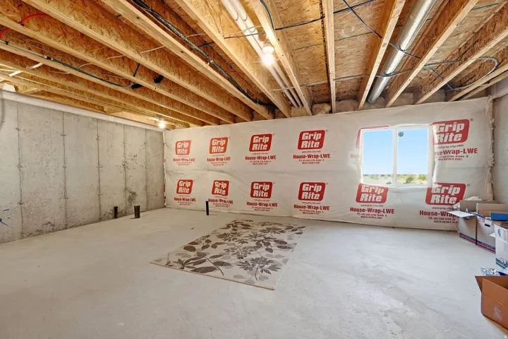 Unfinished basement featuring exposed joists, concrete walls, a window opening, and visible plumbing rough-ins