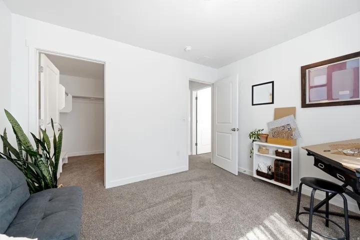 Carpeted room with white walls, baseboards, and two-panel interior doors