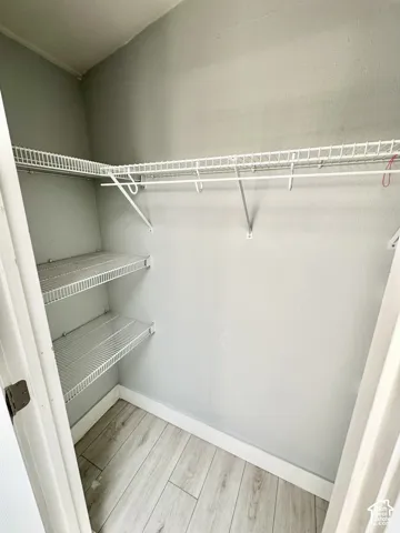 Well-appointed closet featuring wire shelving, a hanging rod, light gray walls, and wood-finish flooring