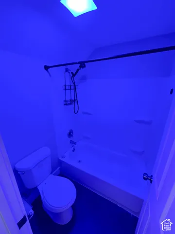 Built-in bathtub with shower head and fixtures, paired with a white toilet