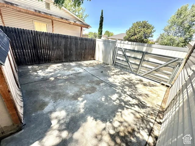 Paved concrete patio area surrounded by a dark wood privacy fence and light-colored siding