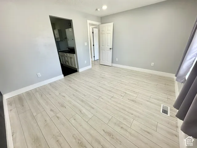Spacious room featuring light wood-finish flooring, recessed lighting, and crisp white baseboards