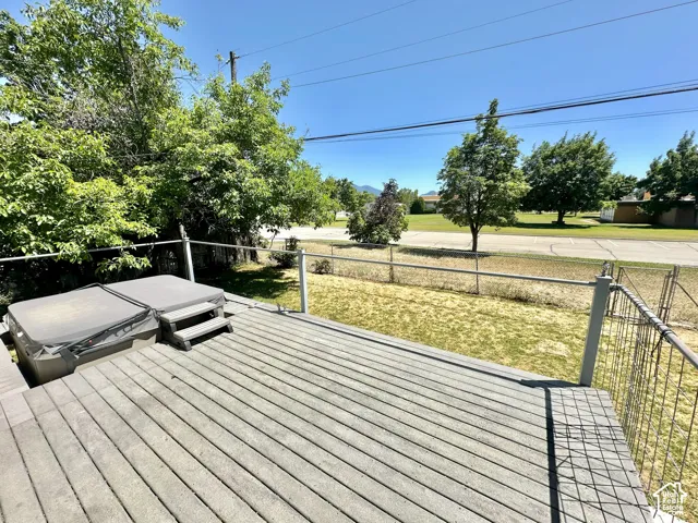 Expansive outdoor deck with composite decking, perimeter metal railing, and a covered hot tub