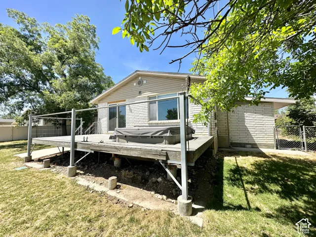 Rear exterior featuring a spacious elevated deck with metal railings and a built-in hot tub