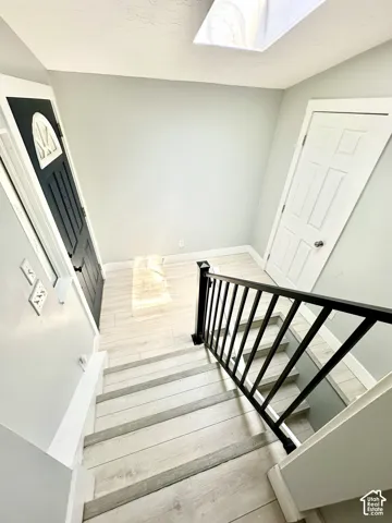 Staircase entry featuring black metal railings and light wood-finish flooring