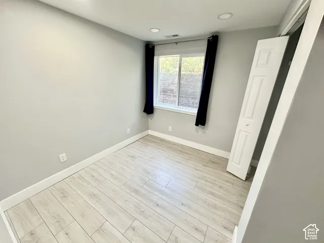 Room with light wood-finish flooring and white baseboards
