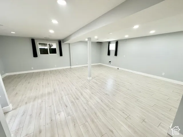 Spacious room featuring light wood-finish flooring, recessed lighting, and crisp white baseboards