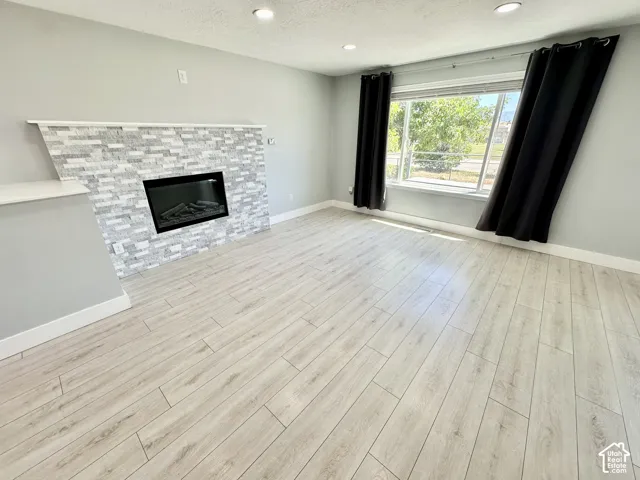 Light wood-finish flooring complements the modern fireplace featuring a stacked stone surround