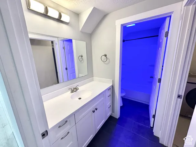 Bathroom featuring a single vanity with a white countertop, undermount sink, and brushed nickel faucet