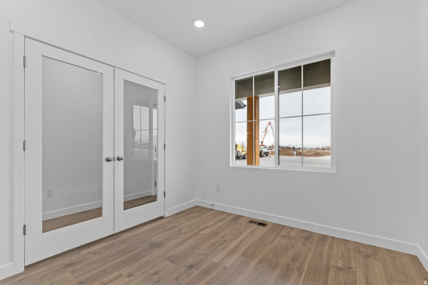 Room featuring wood-finish flooring, recessed lighting, and a large window