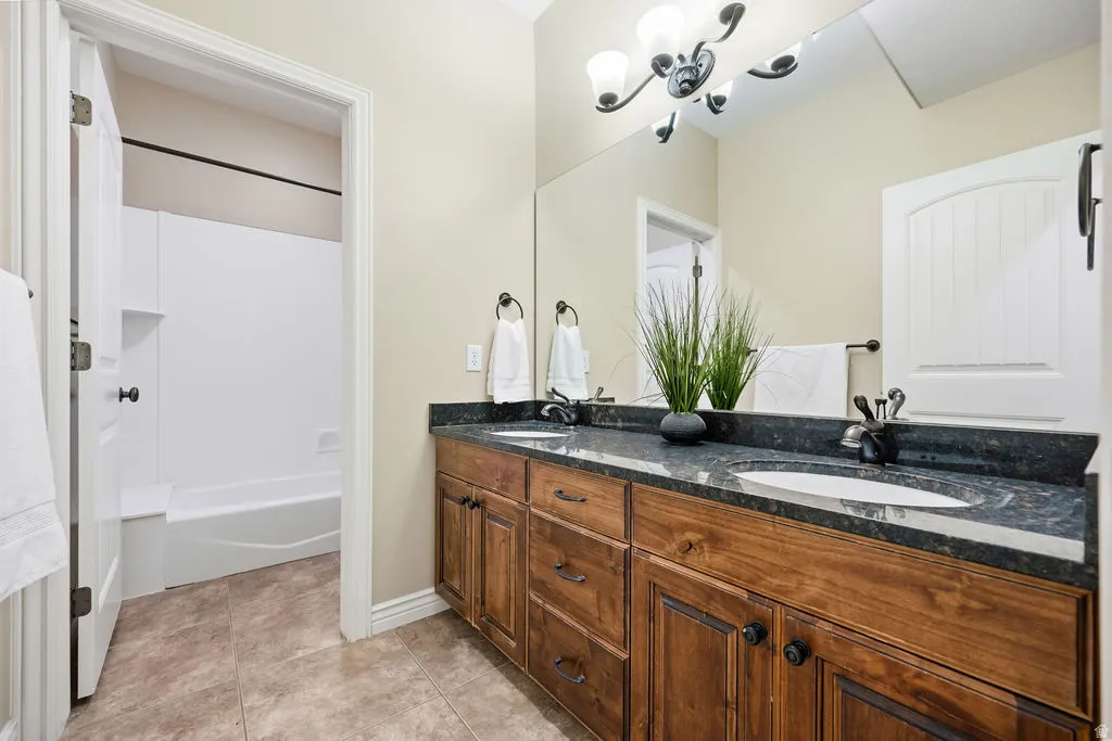 Bathroom featuring a dual vanity with a dark speckled countertop, wood-finish cabinetry, and two undermount sinks