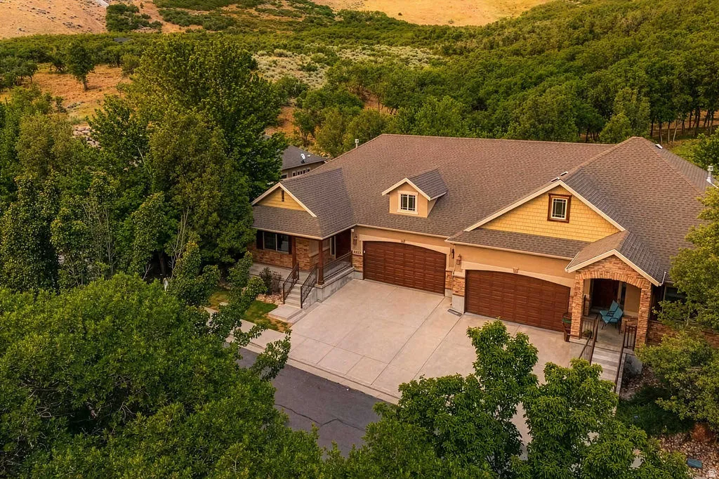 Spacious property featuring an expansive driveway, a three-car garage with wood-finish doors, and a covered entry