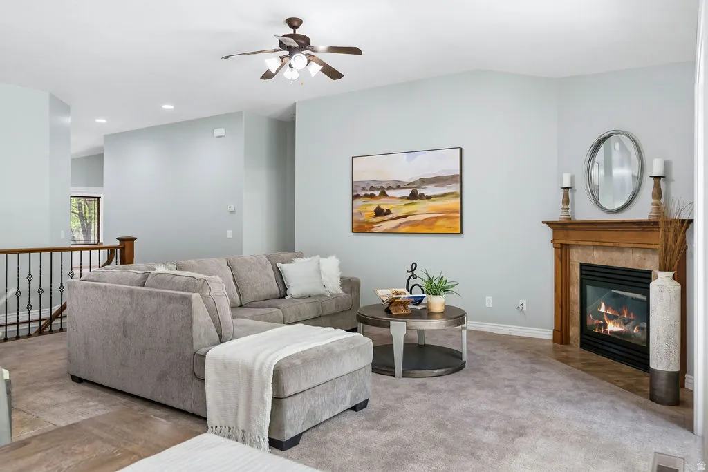 Living area featuring a corner fireplace with a wooden mantel, a ceiling fan, and light gray wall paint