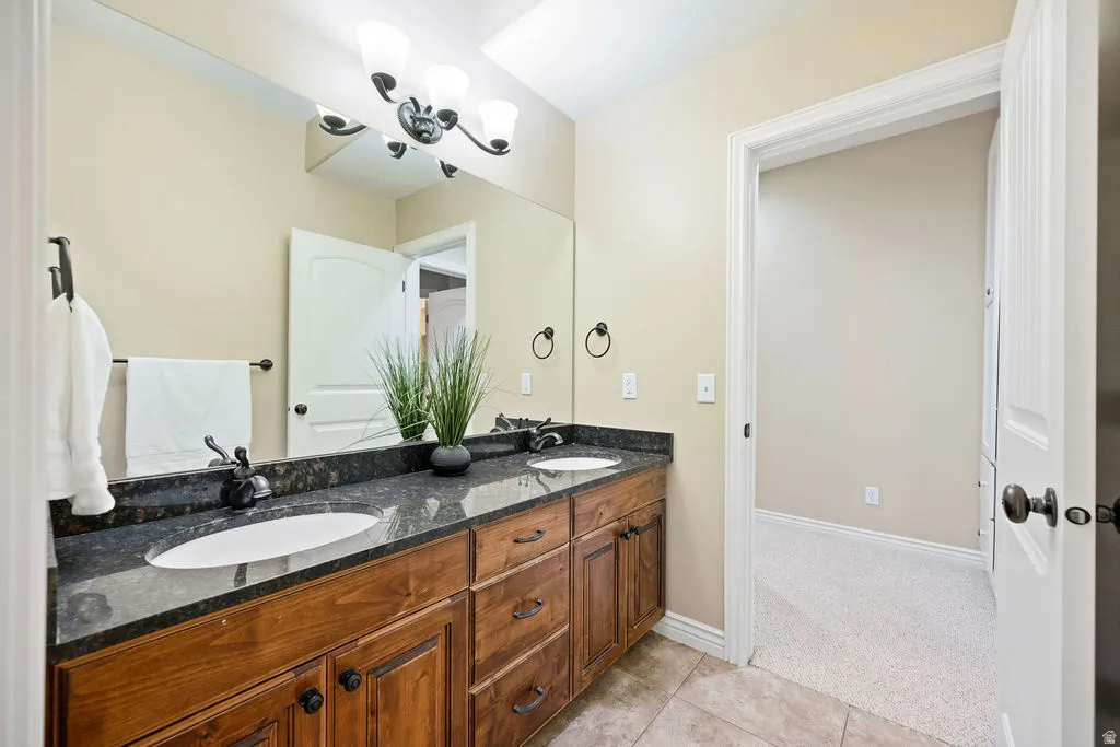 Dual vanity featuring dark stone countertops and wood-finish cabinetry