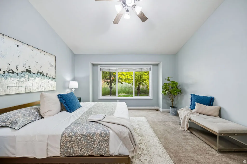 Spacious bedroom featuring light blue walls, recessed window, and a ceiling fan with integrated lighting