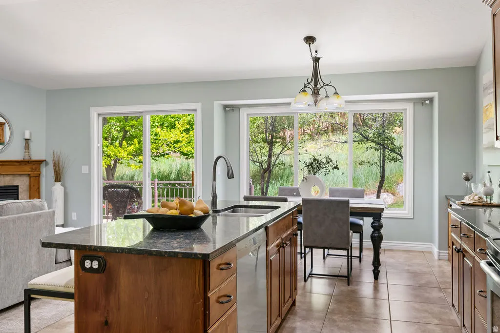 Kitchen island with a dark stone countertop, undermount sink, and integrated dishwasher