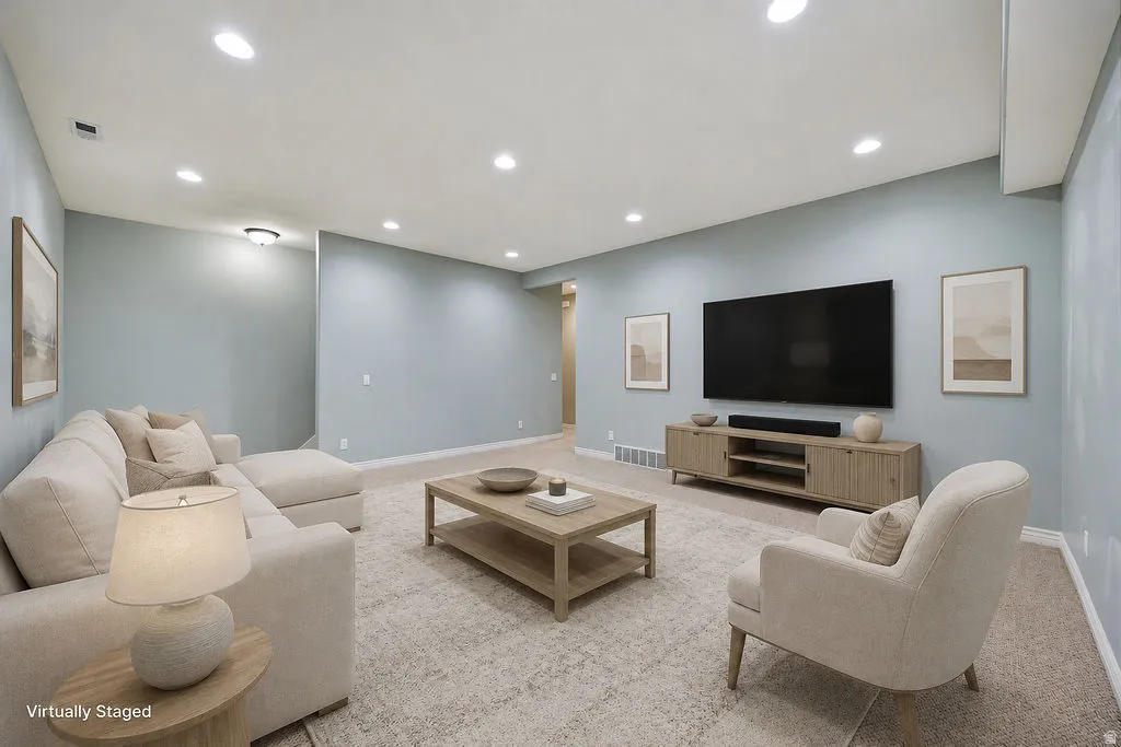 Spacious room featuring light blue walls, recessed ceiling lighting, and neutral carpeting