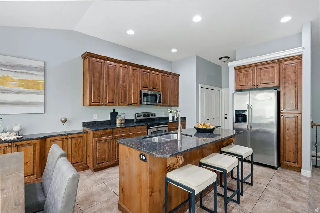 Kitchen featuring wood cabinetry, stainless steel appliances, and a central island with an undermount sink