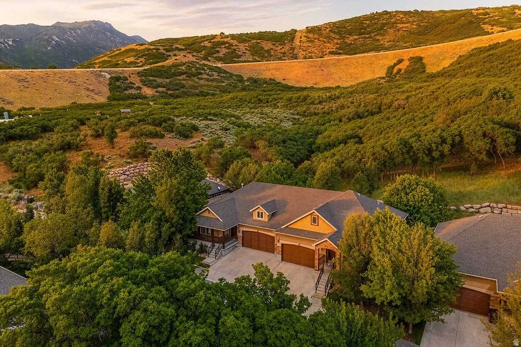 Expansive property featuring a multi-car garage, dormer window accents, stone facade elements, and mature tree landscaping