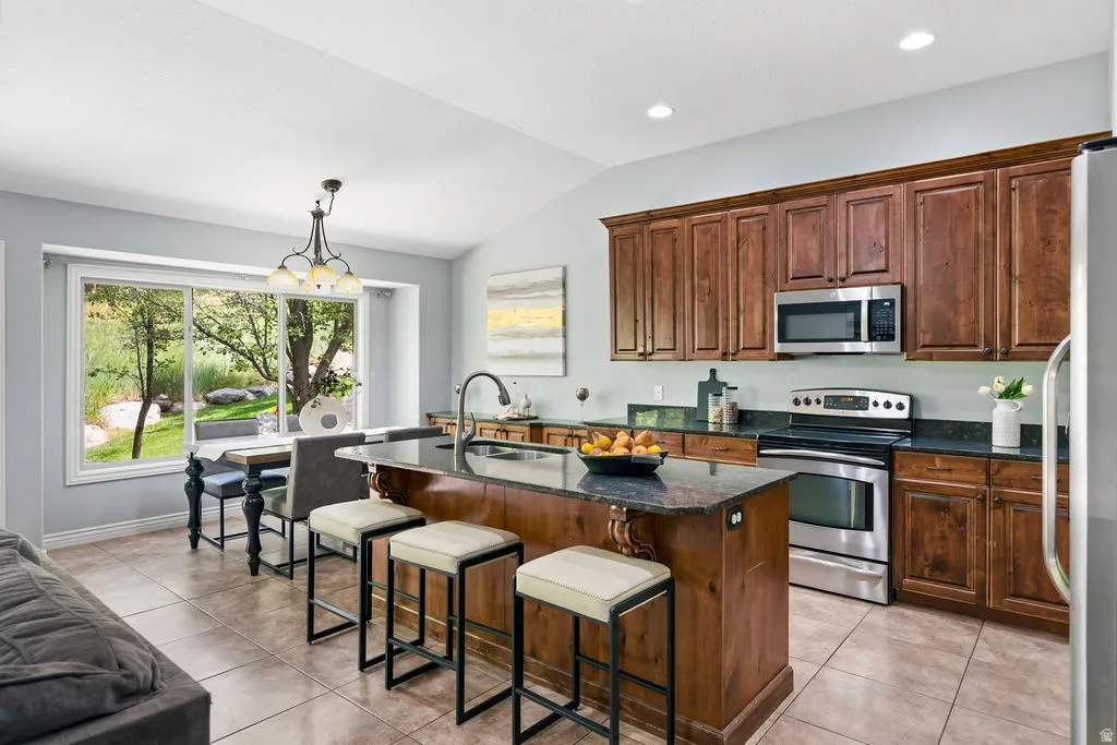 Open-concept kitchen featuring wood-finish cabinetry, stainless steel appliances, and a central island with countertop seating