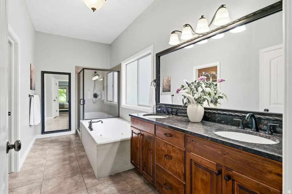 Double vanity with dark countertops and wood-finish cabinetry, featuring dual undermount sinks and dark-finish faucets