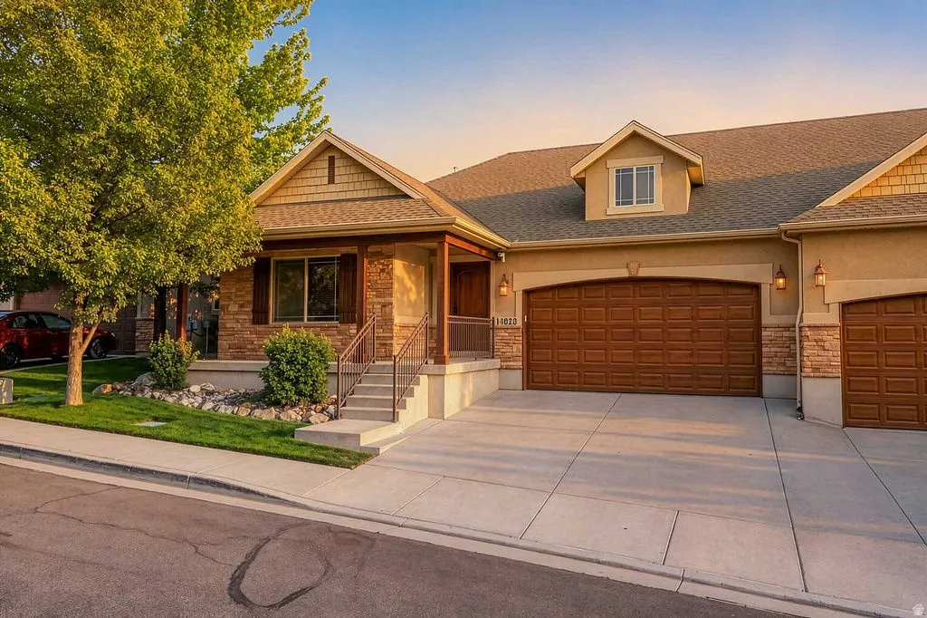 Stucco exterior with stone veneer accents and a prominent front-facing dormer