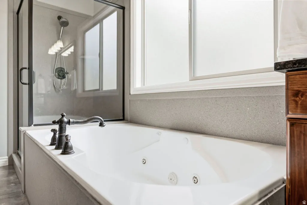 Soaking tub with bronze-finish fixtures, adjacent to a glass-enclosed shower