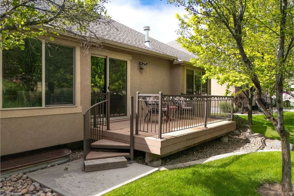 Rear outdoor deck featuring composite decking, decorative metal railing, and a curved staircase