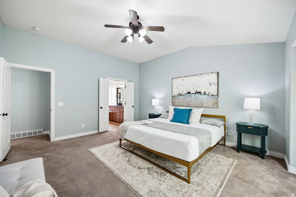Spacious room featuring vaulted ceilings, ceiling fan, and carpeted flooring